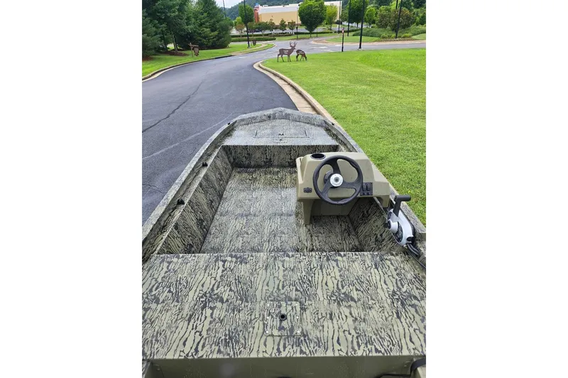 Slide: The Image of 2026 Tracker Grizzly 1648 SC boat with camouflage design on a paved road. - 6