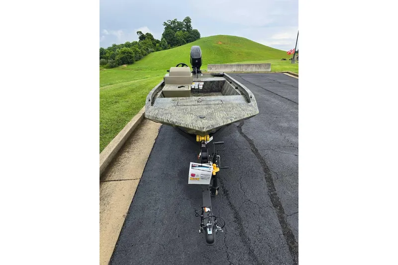 Slide: The Image of 2026 Tracker Grizzly 1648 SC boat on trailer, parked on asphalt near grassy hill. - 7