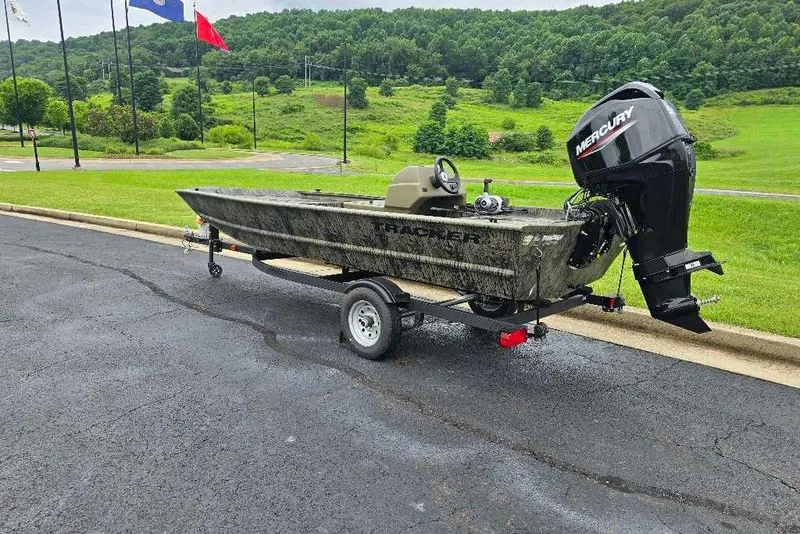 Slide: The Image of 2026 Tracker Grizzly 1648 SC boat on trailer, parked on asphalt with green landscape background. - 5
