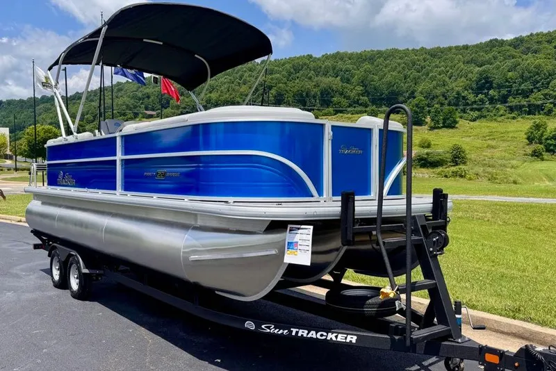 Slide: The Image of 2026 Sun Tracker Party Barge 22 XP3 pontoon boat on trailer, scenic background. - 2