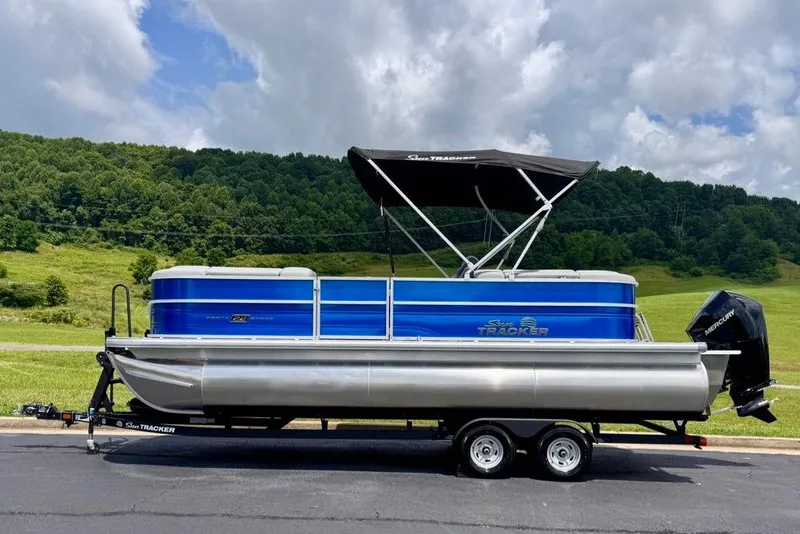 Slide: The Image of 2026 Sun Tracker Party Barge 22 XP3 pontoon boat on trailer, scenic background. - 1