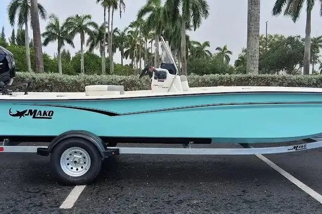 Slide: The Image of 2026 Mako Pro Skiff 17 CC boat on trailer, parked with palm trees in background. - 51