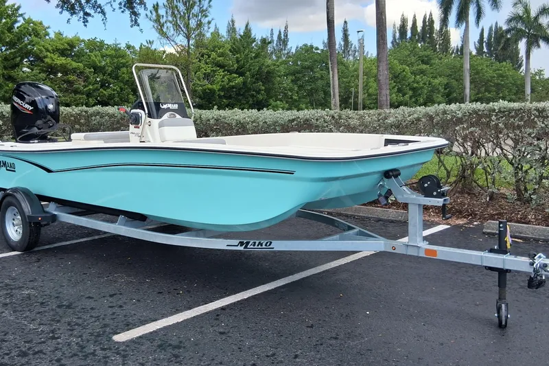Slide: The Image of 2026 Mako Pro Skiff 17 CC boat on trailer, parked outdoors, with lush greenery background. - 50