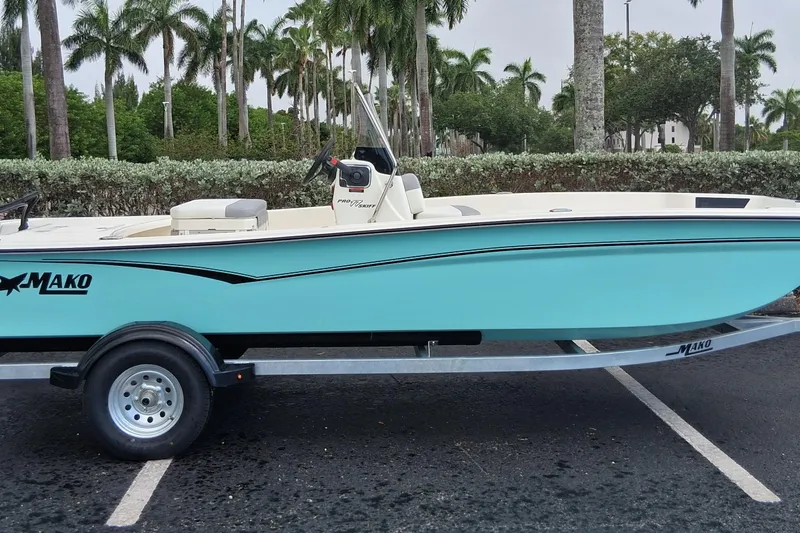 Slide: The Image of 2026 Mako Pro Skiff 17 CC boat on trailer, parked near palm trees. - 1