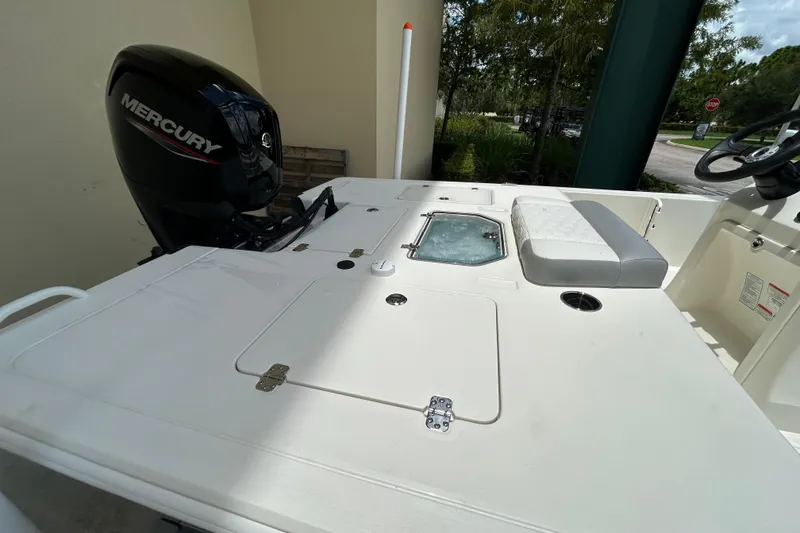 Slide: The Image of 2026 Mako 18 Pro Skiff boat deck with Mercury engine, featuring seating and storage compartments. - 8