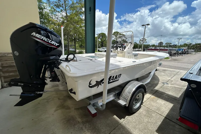 Slide: The Image of 2026 Mako 18 Pro Skiff boat with Mercury engine on trailer, parked outdoors. - 2