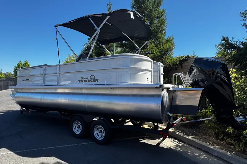 Slide: The Image of 2026 Sun Tracker Party Barge 24 XP3 pontoon boat on trailer, parked outdoors. - 2