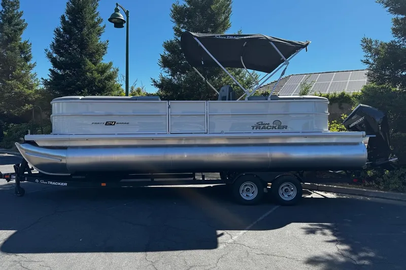 The Image of 2026 Sun Tracker Party Barge 24 XP3 pontoon boat on trailer, parked outdoors. - 0