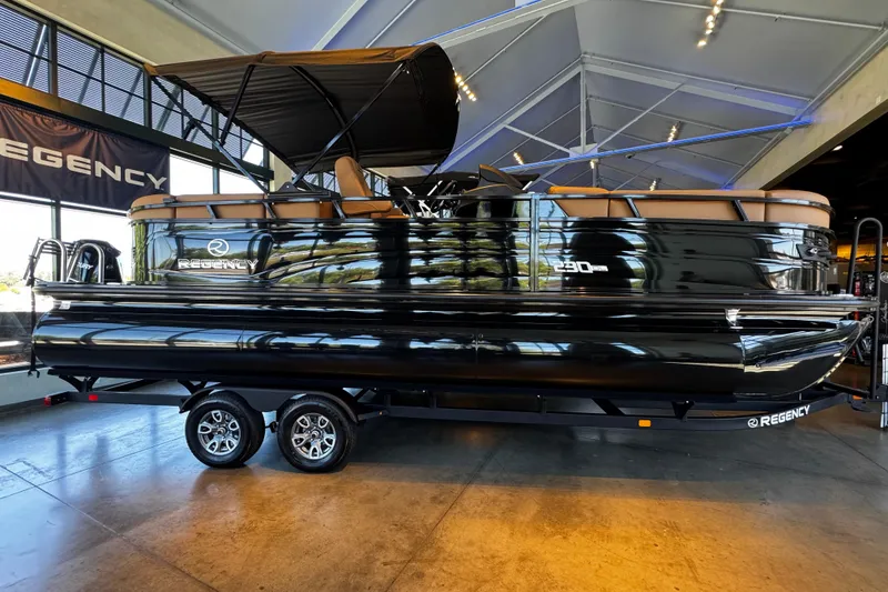 The Image of 2026 Regency 230 DL pontoon boat displayed indoors on a trailer. - 0