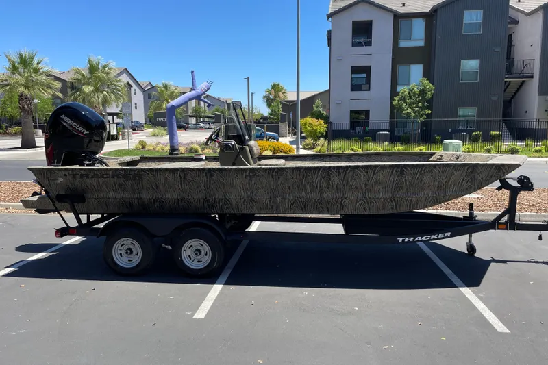 The Image of 2026 Tracker Grizzly 2072 CC boat on trailer in parking lot, with Mercury engine. - 0