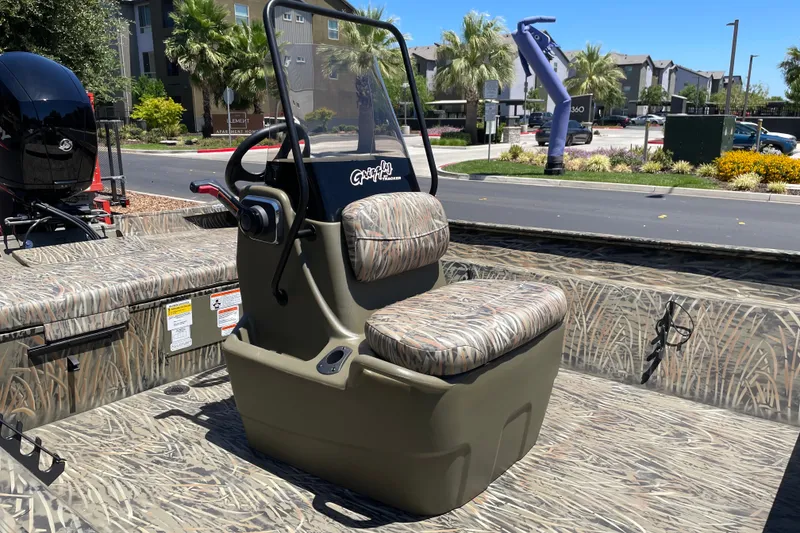 Slide: The Image of 2026 Tracker Grizzly 2072 CC boat with camouflage seating and console, parked outdoors. - 5