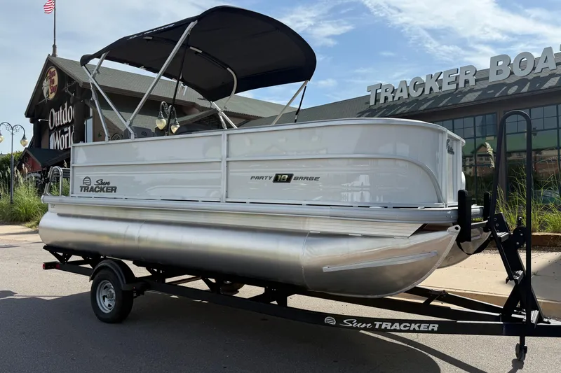 Slide: The Image of 2026 Sun Tracker Party Barge 18 DLX pontoon boat on trailer outside showroom. - 11
