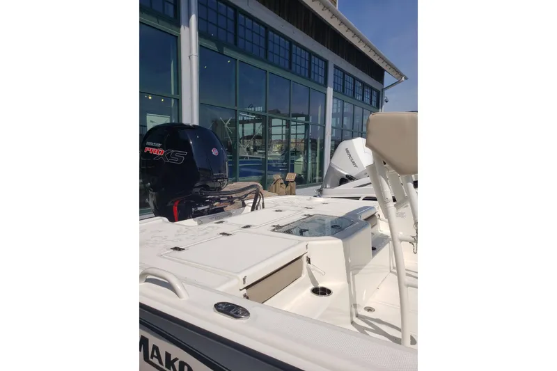 Slide: The Image of 2026 Mako Pro Skiff 19 CC boat with Mercury Pro XS engine, docked near a modern building. - 4