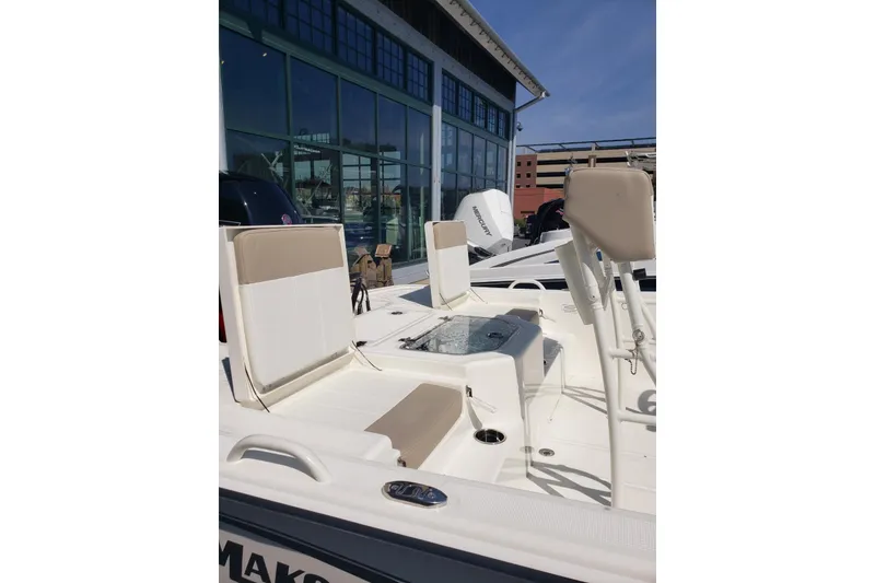Slide: The Image of 2026 Mako Pro Skiff 19 CC boat interior with seating and console, displayed outdoors. - 5