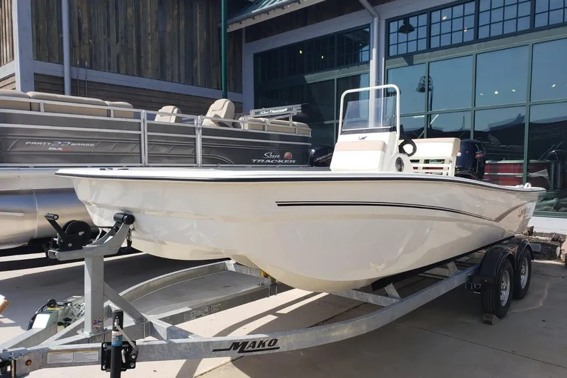 Slide: The Image of 2026 Mako Pro Skiff 19 CC boat on trailer, displayed outdoors near a showroom. - 1