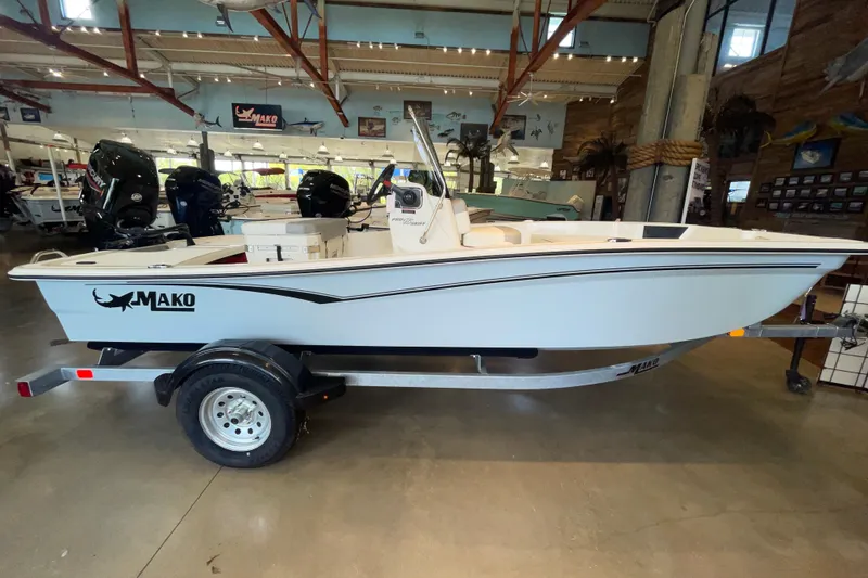 The Image of 2026 Mako Pro Skiff 15 CC boat displayed in a showroom on a trailer. - 0