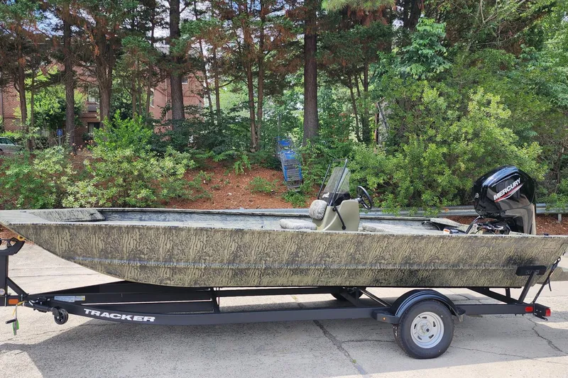 The Image of 2026 Tracker Grizzly 2072 CC boat on trailer, surrounded by lush greenery. - 0