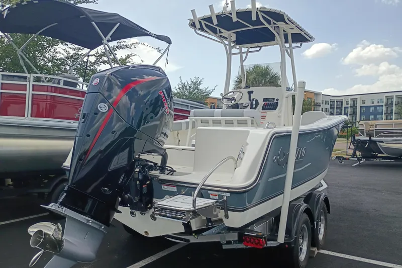 Slide: The Image of 2026 Mako 214 Center Console boat with powerful outboard motor, parked outdoors. - 2