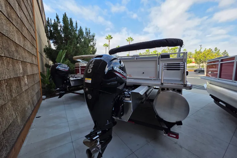 Slide: The Image of 2026 Sun Tracker Party Barge 22 RF XP3 with Mercury outboard motor, parked outdoors. - 1