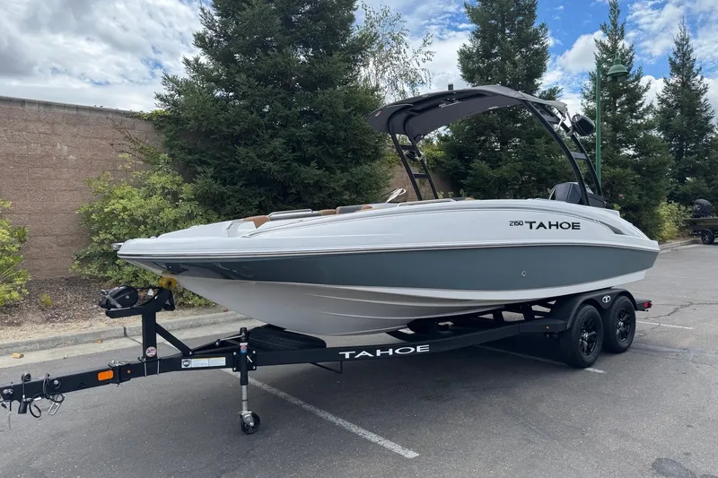 Slide: The Image of 2026 Tahoe 2150 boat on trailer, parked outdoors with trees in background. - 2