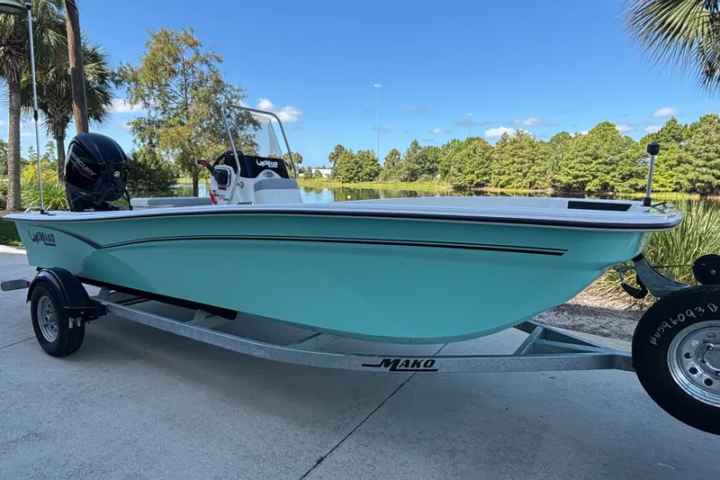 Slide: The Image of 2026 Mako Pro Skiff 17 CC boat on trailer, parked near a scenic lake. - 43