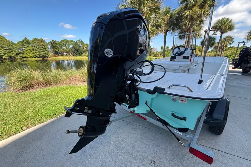 Slide: The Image of 2026 Mako Pro Skiff 17 CC boat with Mercury outboard motor on trailer by a lake. - 45