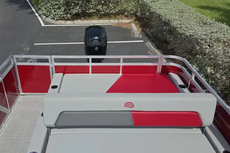 Slide: The Image of 2026 Sun Tracker Party Barge 22 RF DLX with red and gray seating, parked outdoors. - 11