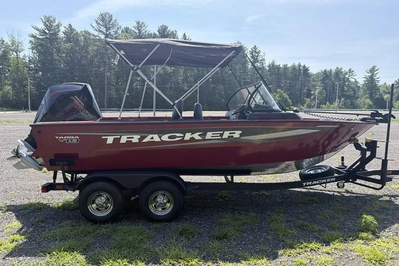 Slide: The Image of 2026 Tracker Targa V-19 WT boat on trailer, parked outdoors with forest background. - 3