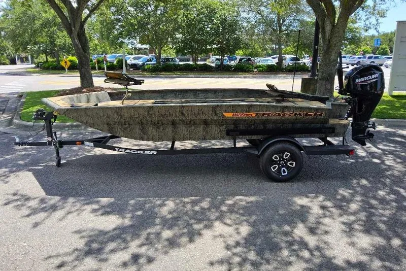 The Image of 2026 Tracker Grizzly 1756 T Marsh boat on trailer, parked under trees. - 0