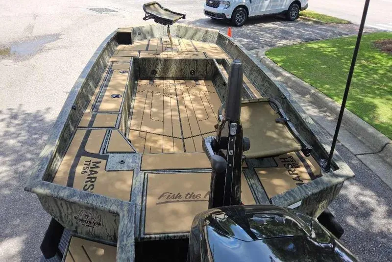 Slide: The Image of 2026 Tracker Grizzly 1756 T Marsh boat with camo design, parked outdoors. - 4