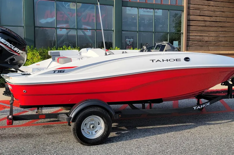 Slide: The Image of 2026 Tahoe T16 boat with red hull on trailer, parked outside showroom. - 1
