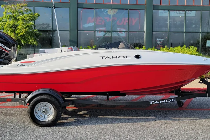 The Image of 2026 Tahoe T16 boat with red hull on trailer, parked outside dealership. - 0