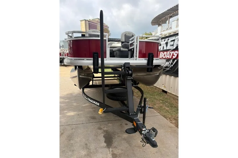 Slide: The Image of 2026 Sun Tracker Bass Buggy 18 DLX pontoon boat on trailer, parked outdoors. - 13