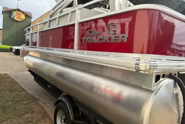 Slide: The Image of 2026 Sun Tracker Bass Buggy 18 DLX pontoon boat, red exterior, parked outdoors. - 17