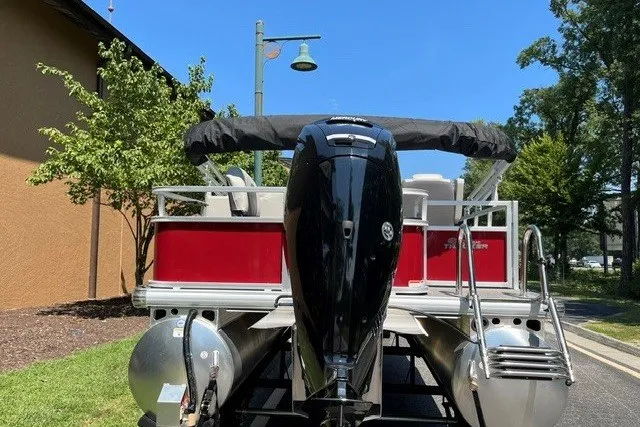 Slide: The Image of 2026 Sun Tracker Bass Buggy 18 DLX pontoon boat with outboard motor, parked outdoors. - 19