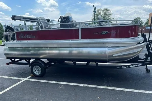 The Image of 2026 Sun Tracker Bass Buggy 18 DLX pontoon boat on trailer in parking lot. - 0