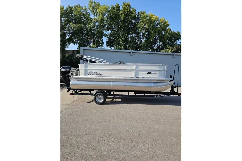 The Image of 2026 Sun Tracker Party Barge 18 DLX pontoon boat on trailer, parked outdoors. - 0