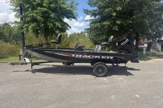 The Image of 2026 Tracker Pro Team 175 boat on trailer, parked outdoors, surrounded by trees. - 0