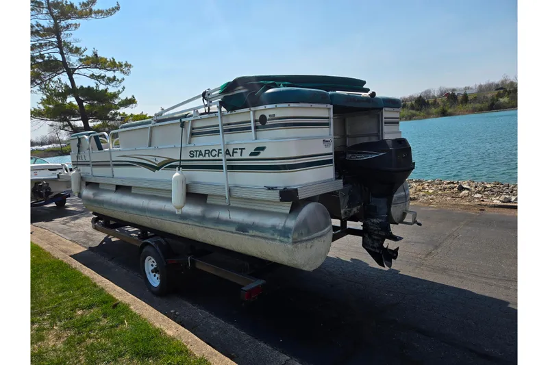 Slide: The Image of 1998 Starcraft pontoon boat on trailer by a lake, ready for transport. - 1