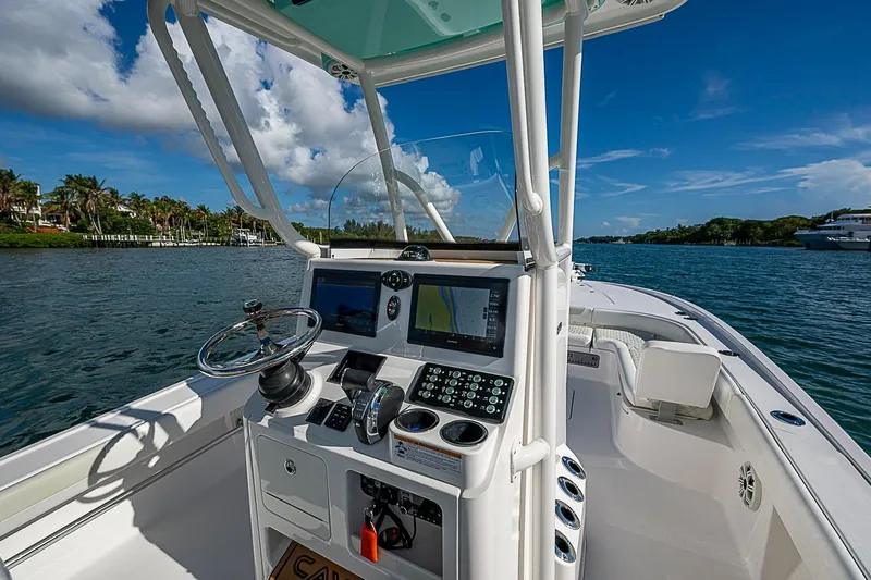 Slide: The Image of 2020 Caymas 28 HB boat cockpit with steering wheel and navigation screens on a sunny day. - 24