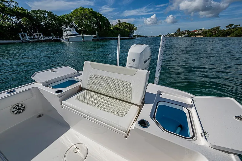 Slide: The Image of 2020 Caymas 28 HB boat with cushioned seating and storage compartments on a scenic waterway. - 17