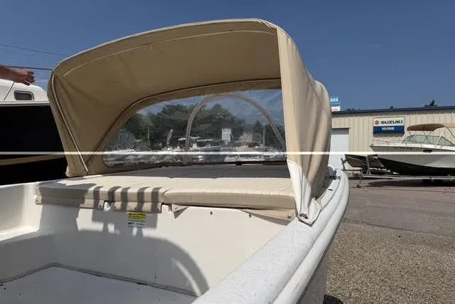 Slide: The Image of 2018 Carolina Skiff 22 Ultra Elite boat with beige canopy in a marina setting. - 14