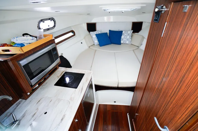 Slide: The Image of 2020 Pursuit OS 325 Offshore cabin interior with kitchenette and cozy seating area. - 25