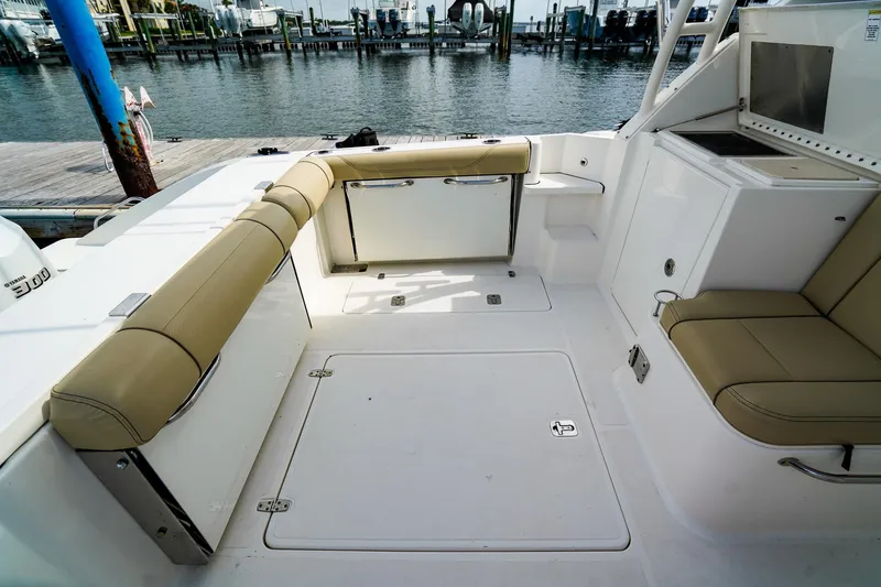Slide: The Image of 2020 Pursuit OS 325 Offshore boat interior with beige seating and dockside view. - 12