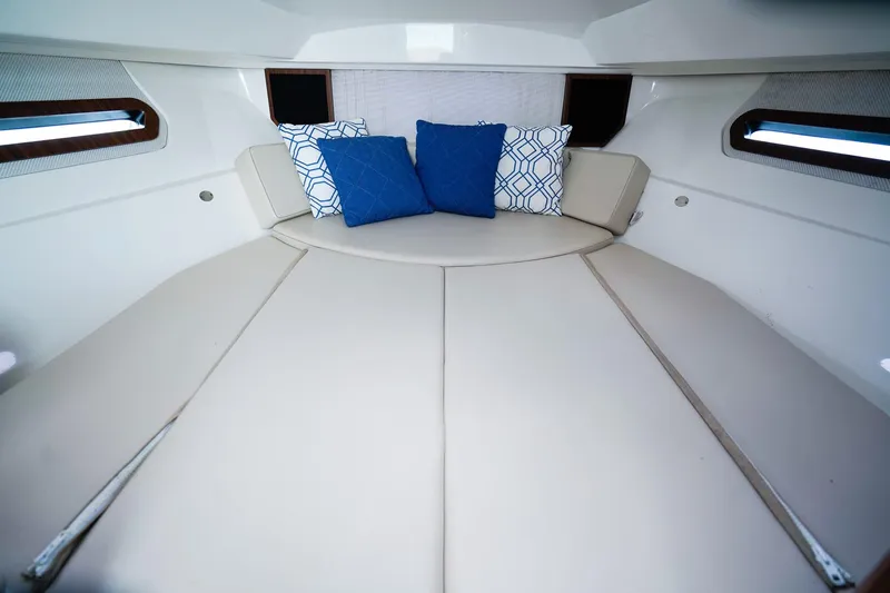 Slide: The Image of 2020 Pursuit OS 325 Offshore cabin interior with cushioned seating and decorative pillows. - 26