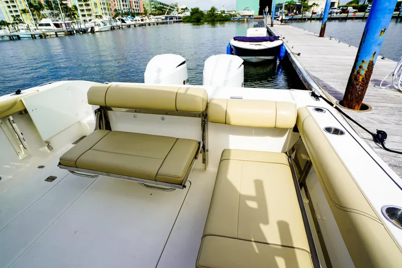 Slide: The Image of 2020 Pursuit OS 325 Offshore boat interior with beige seating at marina dock. - 11
