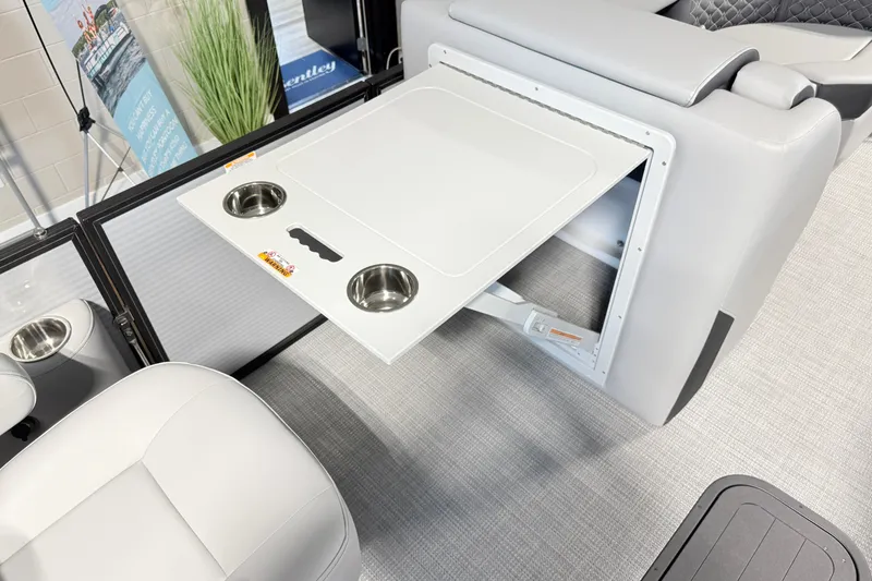 Slide: The Image of 2026 Manitou Encore SL SHP575 boat interior with fold-out table and cup holders. - 5