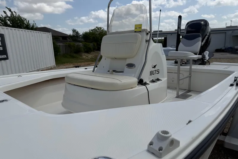 Slide: The Image of 2012 Mako 18 LTS boat with seating and console, parked outdoors under cloudy sky. - 15