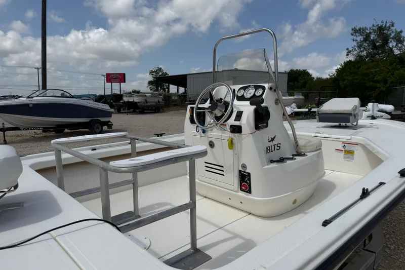 Slide: The Image of 2012 Mako 18 LTS boat interior with steering console and seating, under a cloudy sky. - 9