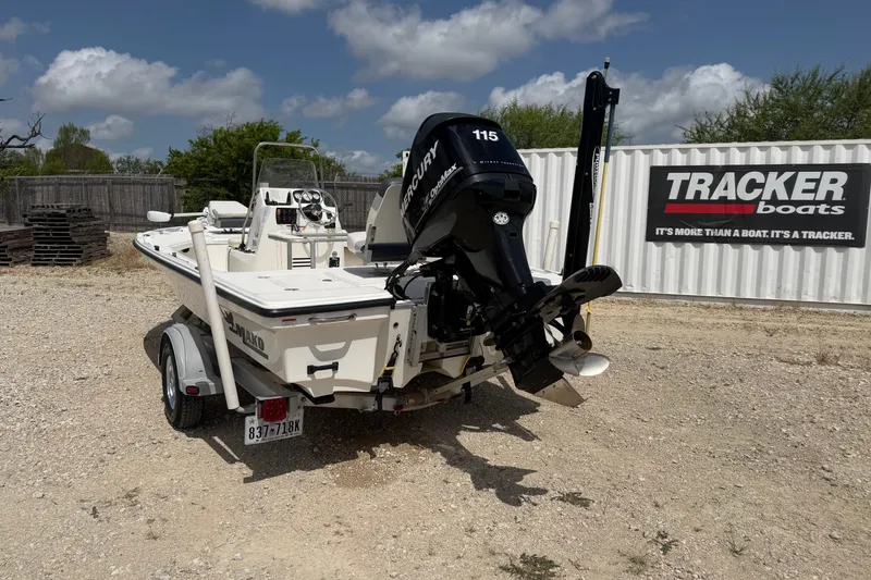 Slide: The Image of 2012 Mako 18 LTS boat with Mercury engine, parked on gravel near Tracker Boats sign. - 2